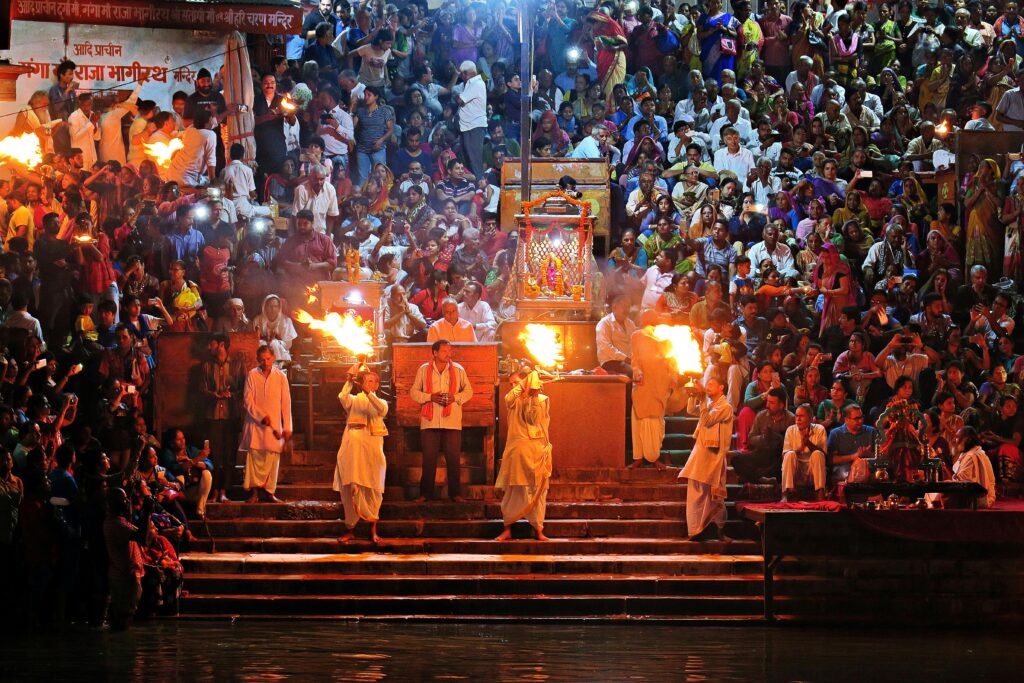 A vibrant crowd attends a Hindu Aarti ritual on the riverbanks, showcasing cultural traditions.